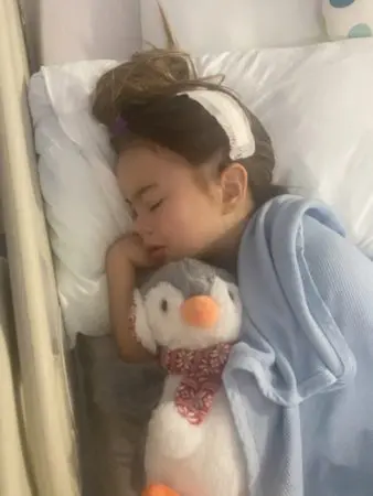 A photo of Kara, laying in a hosptial bed, straight after surgery