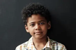 Boy facing camera in front of black background