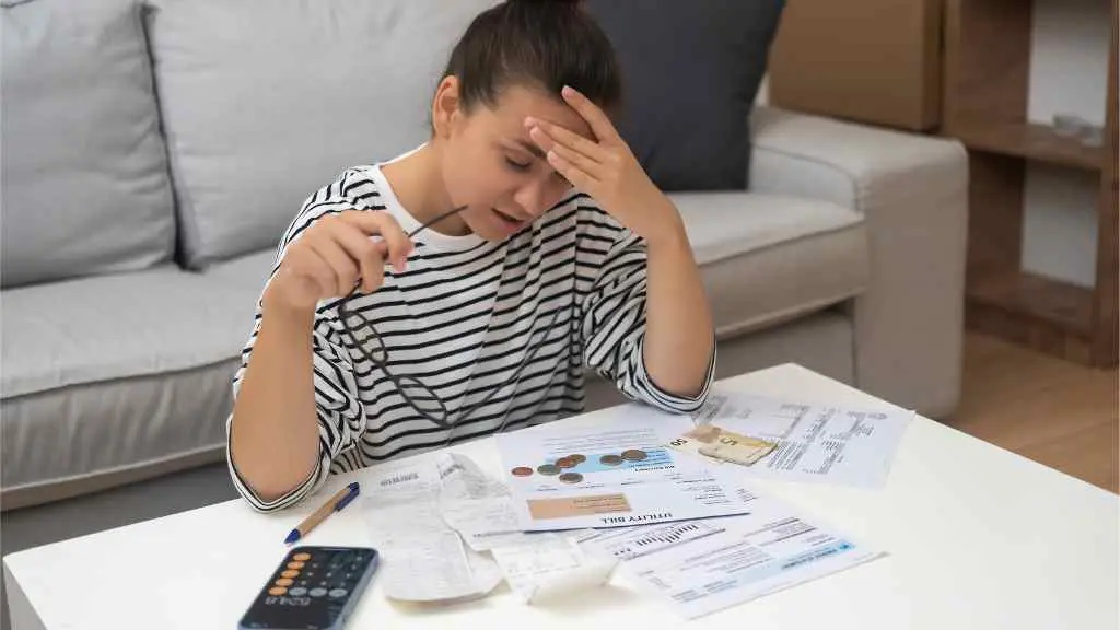 Woman with head in hands looking at bills