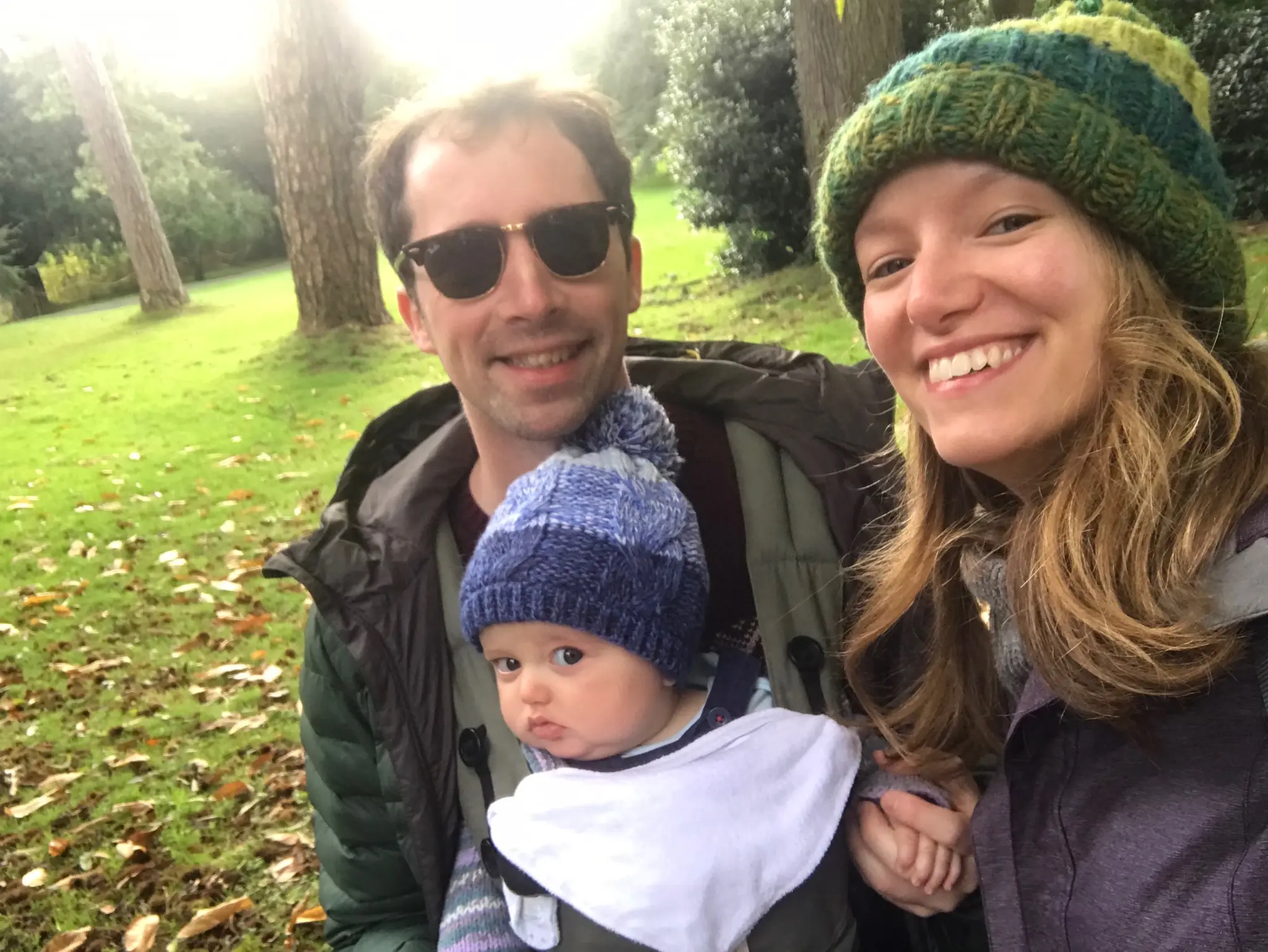 Amy and Matt with baby Rory. They are all smiling and wearing woolly hats and coats outside.