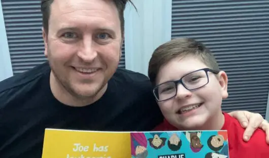 Tim and his son Michael are together holding the original version of the storybook and the new updated storybook