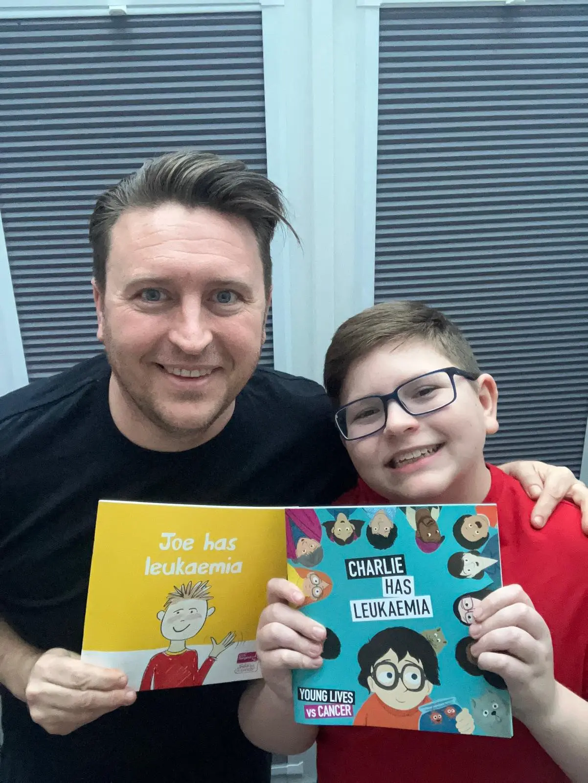 Tim and his son Michael are together holding the original version of the storybook and the new updated storybook